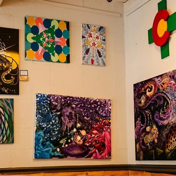 A wall covered with various colorful, abstract, and psychedelic paintings, with a TV screen in the corner.